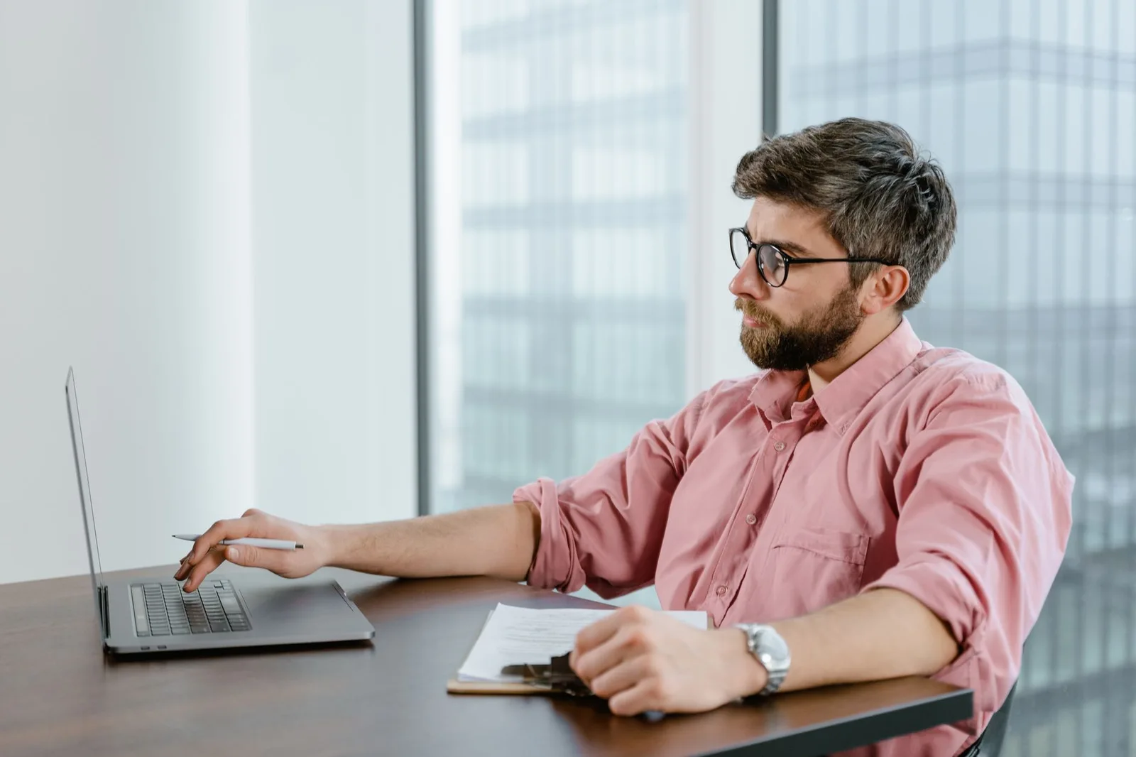 Professional working at a laptop beside an office window